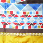 Silk scarf with hand rolled edges and a gold border with a classic central design in grey, blue and red.