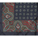 Dark blue background silk pocket square with a red green and white paisley border and a small central design