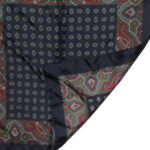 Dark blue background silk pocket square with a red green and white paisley border and a small central design