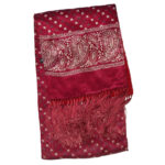 Long dark red scarf which is patterned silk with a paisley border one side and plain wool the other